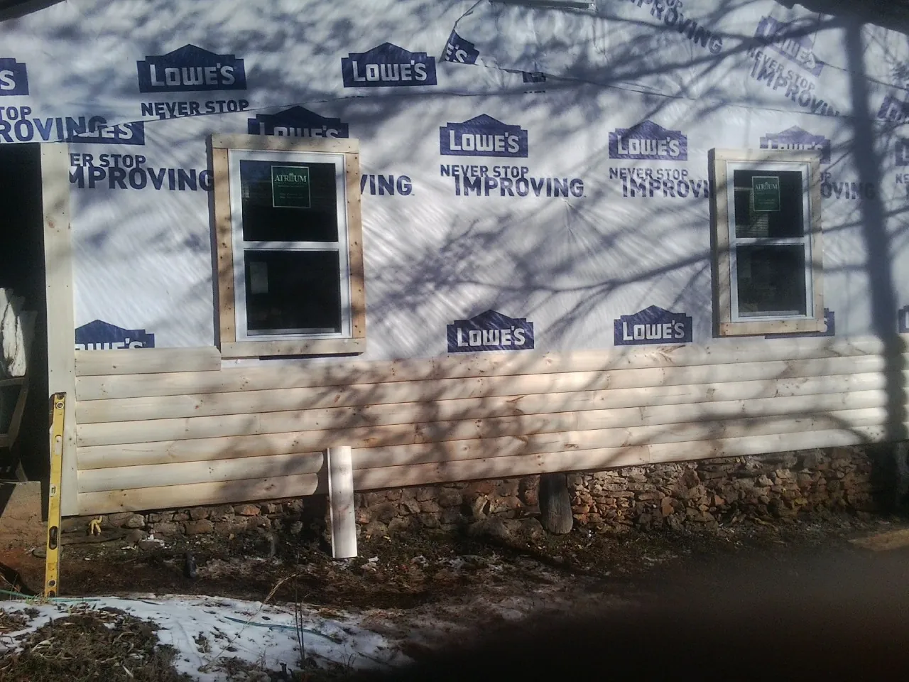 House wrap and new log siding going up on an exterior wall in Deal