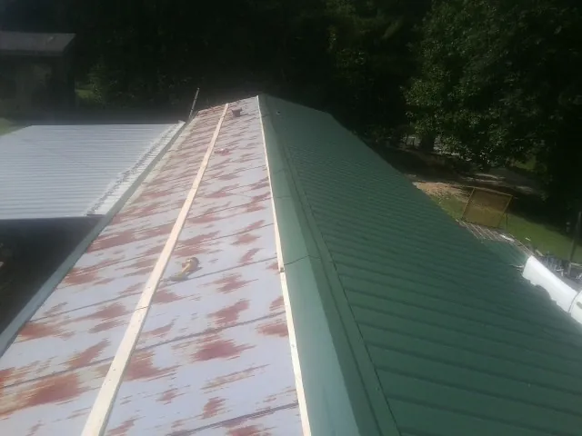 Old rusted panels beside newly installed green metal roofing — Wind Damage Roof Repair by Roofing Brothers in Deal