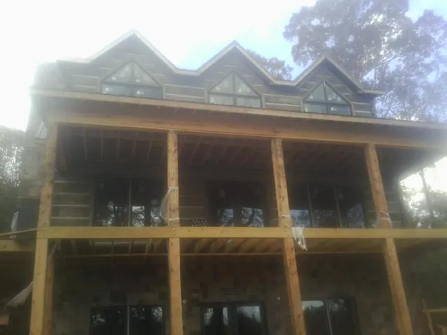 Dormers and porch framing on a large log home under construction — Roof Coating work by our crew in Deal