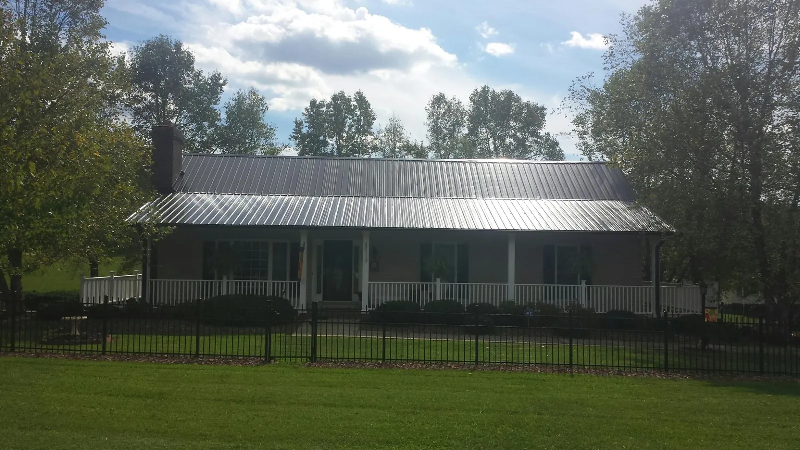 Gray metal roof on a brick ranch with a full width front porch — Gutter Guard Installation work by our crew in Deal