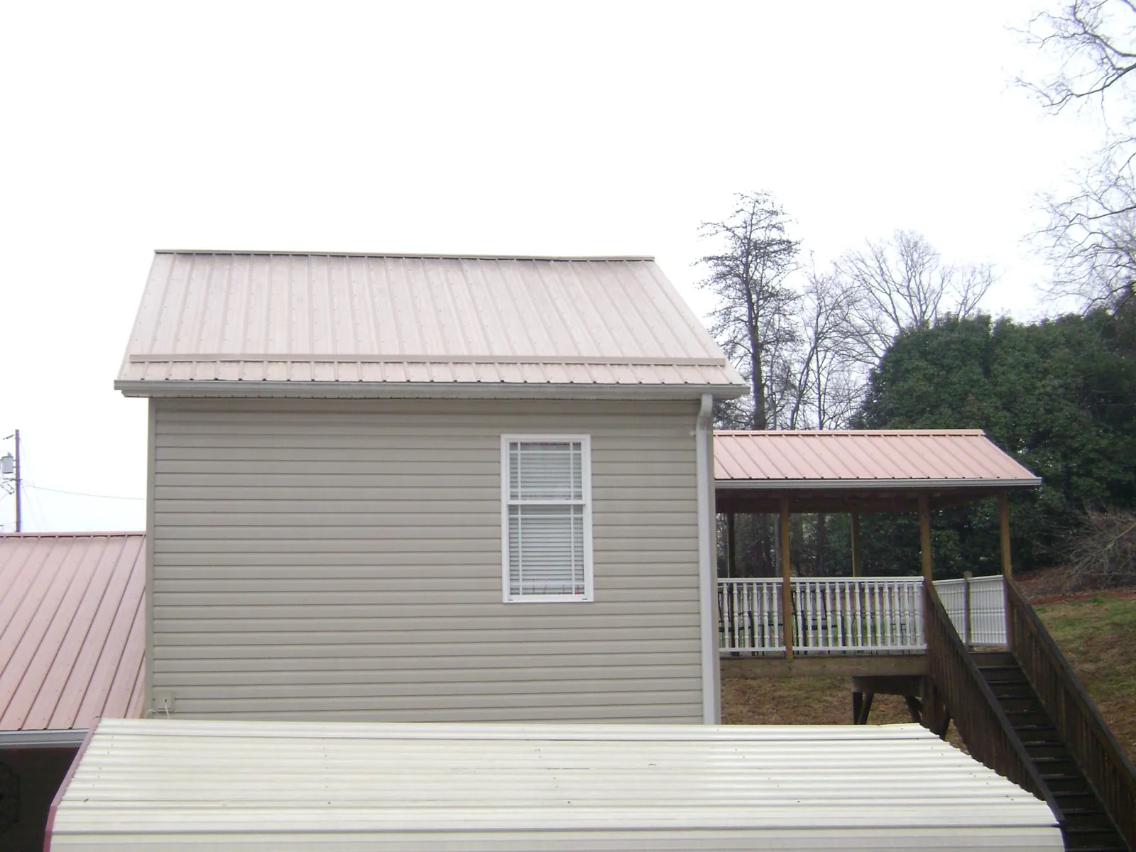 Tan metal roofs on a two story addition and attached porch, from a Roof Replacement job in Deal